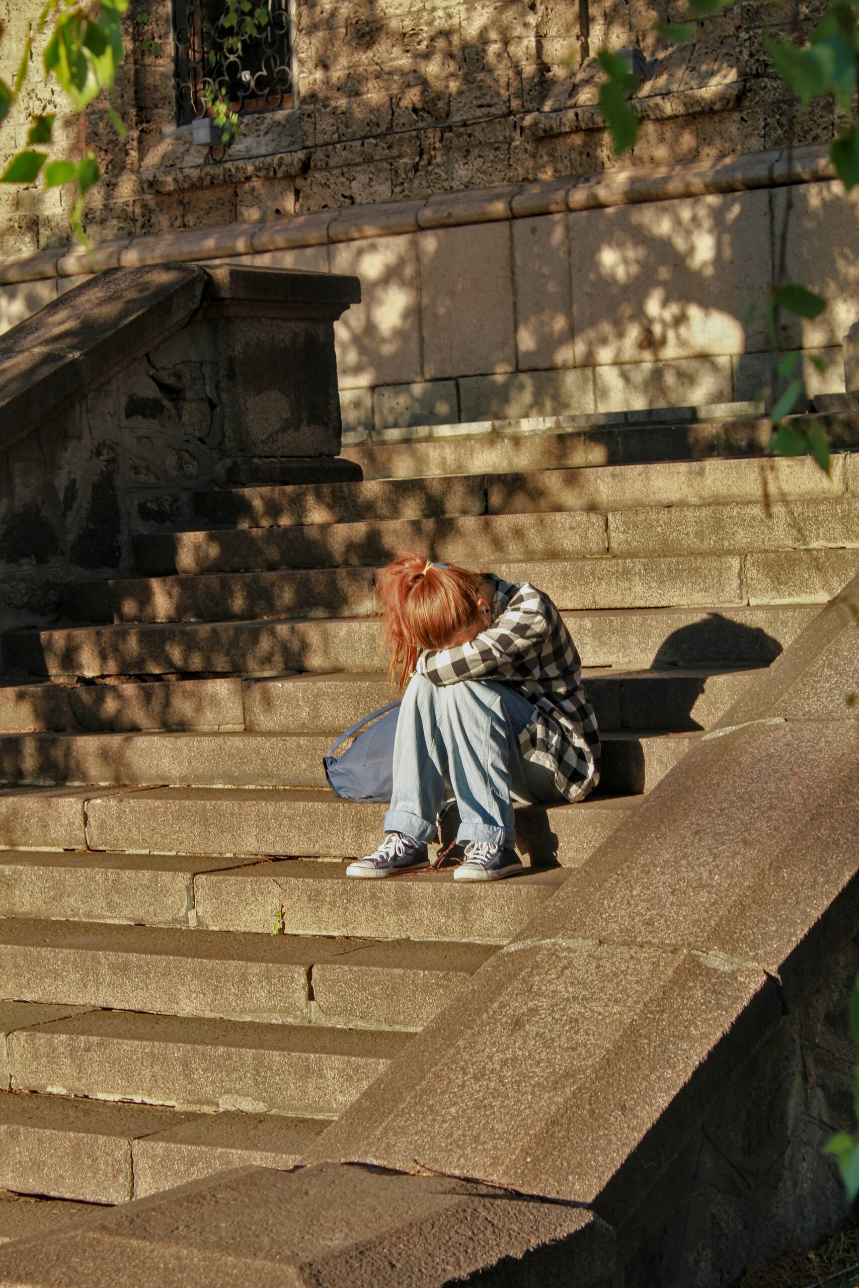a teen girl sitting on a stairs in discomfort