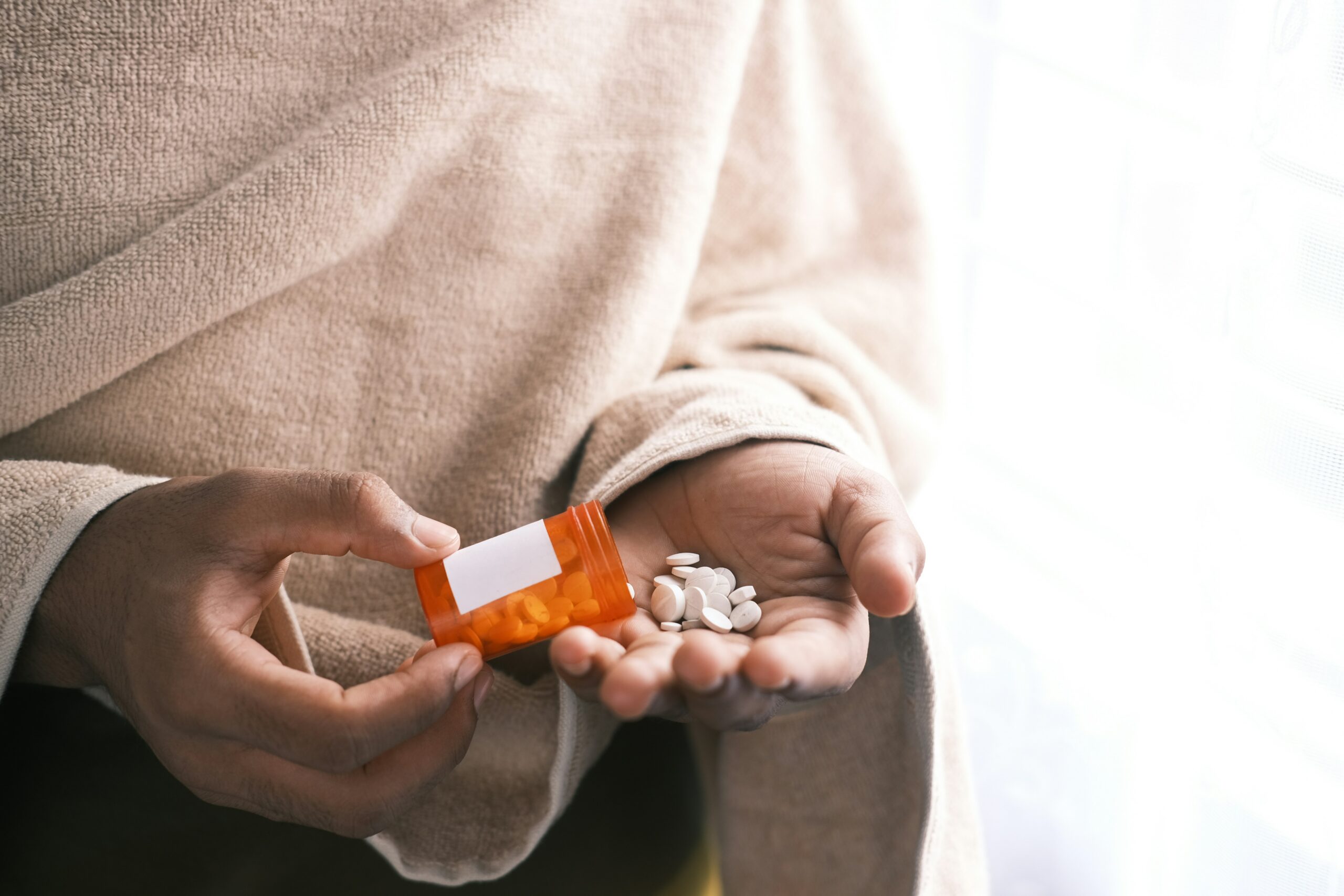 Person pouring pills from a prescription bottle