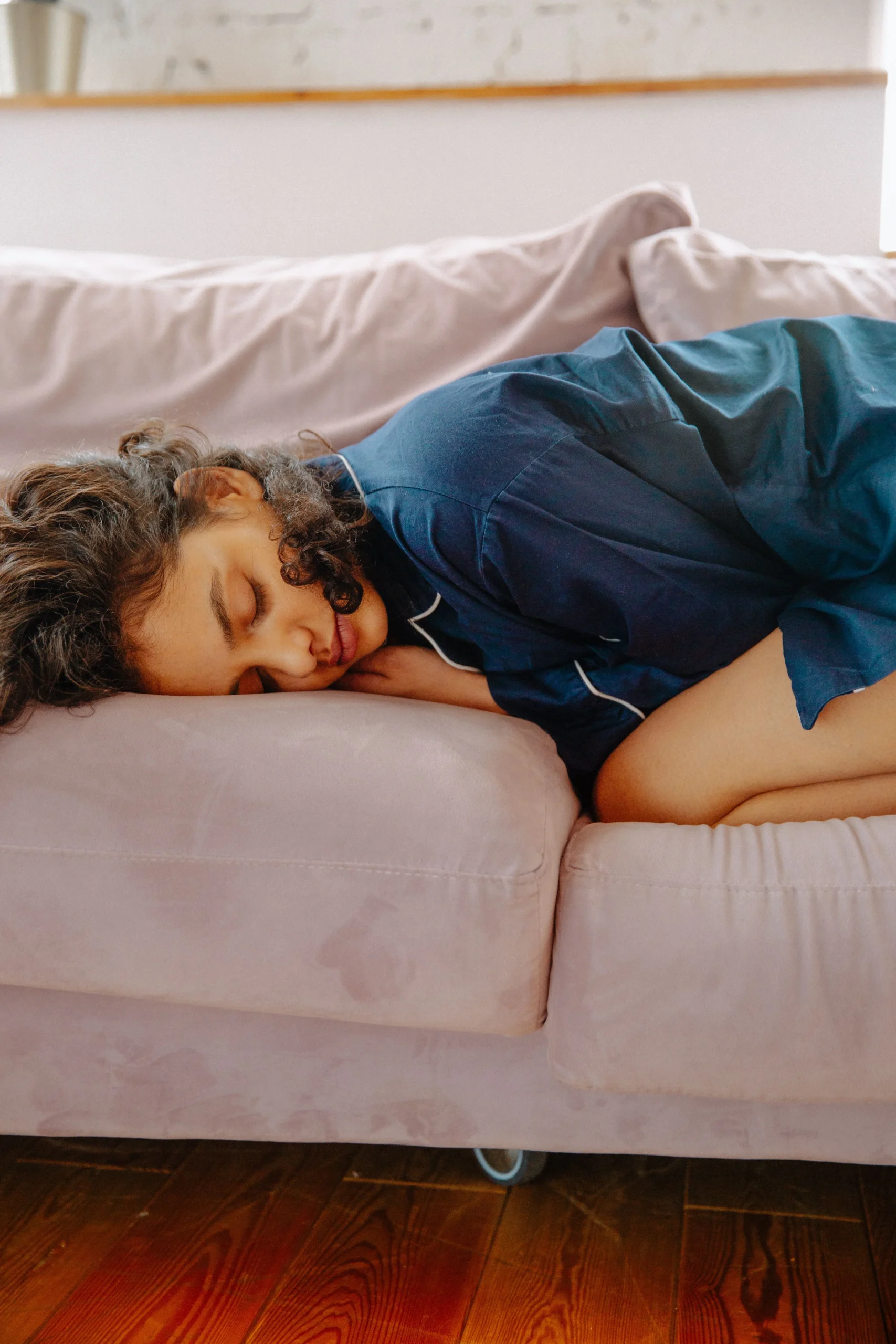 A woman resting on the couch in pain